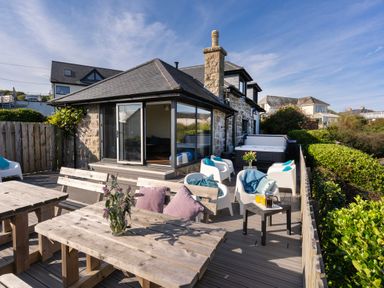 A patio with wooden tables and chairs outside a stone house at Rocky Close in St Ives