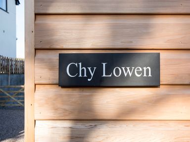 A black sign with white text saying Chy Lowen mounted on a wooden wall at Chy Lowen in St Ives