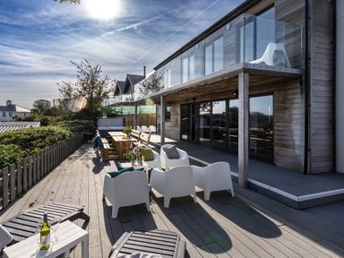 An outdoor patio with white chairs wooden tables and loungers at Chy Lowen in St Ives