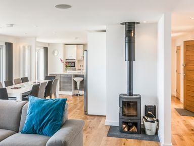 An open living room and kitchen area with a wood burning stove and dining table at Boscarne St Ives
