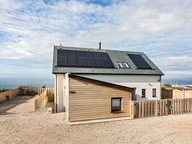 A house with solar panels on the roof and a fenced gravel driveway at Boscarne in St Ives
