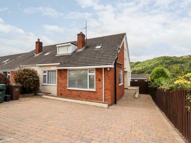 A semi detached house with a paved driveway and a wooden fence at 4 Bodnant Road in Rhos-On-Sea
