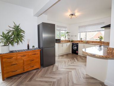 A kitchen with a wooden dresser and plants near windows at 4 Bodnant Road in Rhos-On-Sea