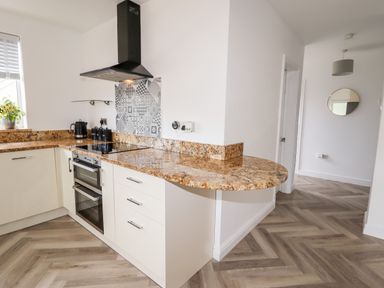 A kitchen with granite countertops black oven and stovetop in a home at 4 Bodnant Road in Rhos-On-Sea