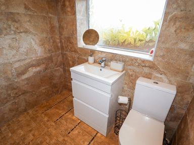 A bathroom with a white sink cabinet and a toilet next to a frosted window at 4 Bodnant Road in Rhos-On-Sea