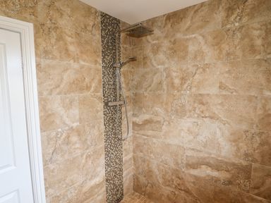 A shower area with beige tiled walls and a vertical strip of small mosaic tiles at 4 Bodnant Road in Rhos-On-Sea