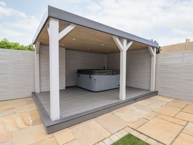 A covered outdoor hot tub on a wooden deck with a fenced patio at 4 Bodnant Road in Rhos-On-Sea