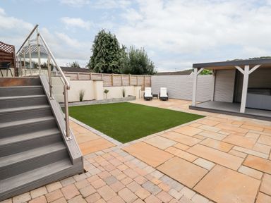 A backyard with stairs a patch of grass two lounge chairs and a covered patio area at 4 Bodnant Road in Rhos-On-Sea