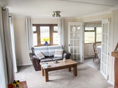 A living room with a brown leather sofa coffee table and flowers on a side table at The Dovecote in Hartland