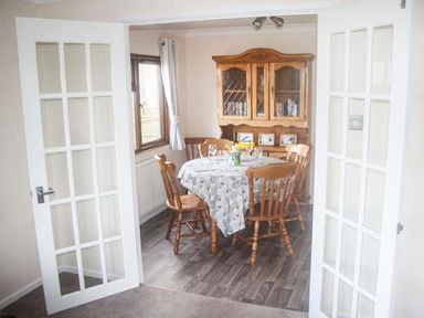 A dining room with a table and wooden chairs a wooden cabinet and a window at The Dovecote in Hartland