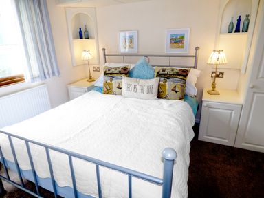 A bedroom with a metal bed frame white quilt pillows bedside tables and lamps at The Dovecote in Hartland