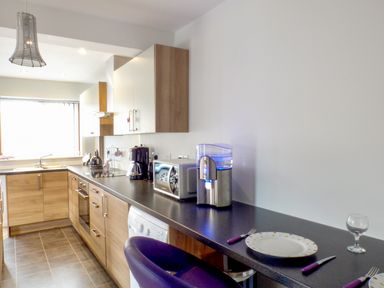 A kitchen with wooden cabinets a black countertop appliances and a set dining area at Penylodge in Builth Wells