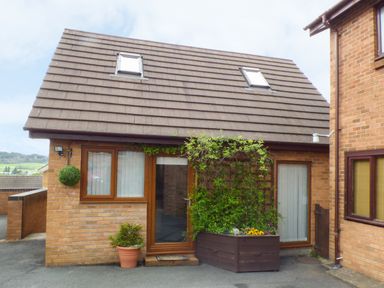 A brick house with two skylights two windows a glass door and plants outside at Penylodge in Builth Wells
