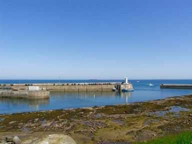 A harbor with a pier and parked cars beside the sea at Sunnie Cottage in Seahouses