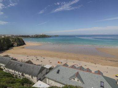 A beach with people on the sand and buildings in the foreground at 5 Ocean Heights in Newquay