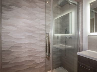 A shower enclosure with glass door next to a sink and mirror in a bathroom at 5 Ocean Heights in Newquay