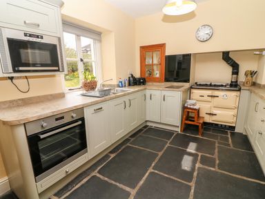 A kitchen with built in oven microwave sink and vintage stove at Waingate Cottage in Flookburgh