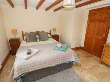 A bedroom with a double bed two bedside tables lamps wooden door and a wooden dresser at Y Cartws in Nevern near Cardigan