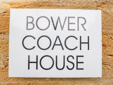 A sign with the text Bower Coach House on a stone wall at Bower Coach House in Bower Hinton near Martock