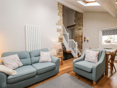 A living room with a blue sofa and armchair a side table with lamp and a staircase at Bower Coach House in Bower Hinton near Martock