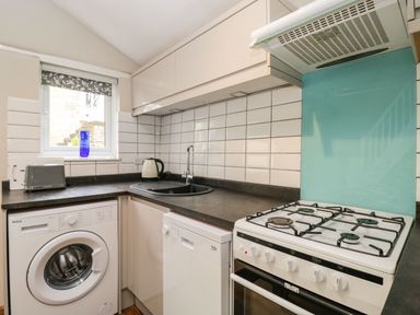 A kitchen with a washing machine dishwasher gas stove toaster kettle and sink at Bower Coach House in Bower Hinton near Martock