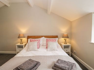 A bedroom with a bed with pillows and blankets bedside tables with lamps at Bower Coach House in Bower Hinton near Martock