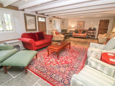 A living room with multiple armchairs and sofas around a wooden coffee table on a patterned rug at Ros Vale in St Buryan