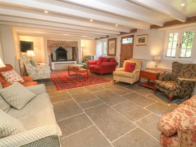 A living room with multiple armchairs a sofa a coffee table a fireplace and a red rug at Ros Vale in St Buryan