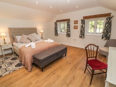 A bedroom with a bed lamps bedside tables two windows and chairs at Ros Vale in St Buryan