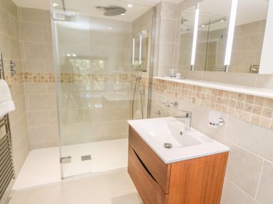 A bathroom with a wooden vanity basin and a glass-enclosed walk-in shower at Ros Vale in St Buryan