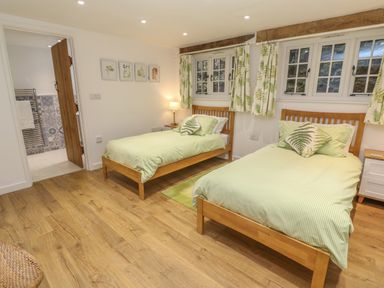 A bedroom with two single beds and green bedding with leaf patterns at Ros Vale in St Buryan