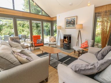 A living room with sofas armchairs a coffee table and a fireplace at Ros Vale in St Buryan