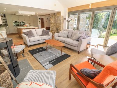 A living room with sofas armchairs a coffee table a rug and large windows at Ros Vale in St Buryan