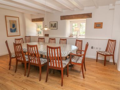 A dining room with wooden chairs around a large oval table at Ros Vale in St Buryan