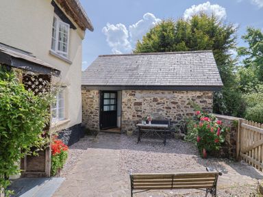 An outdoor area with a bench and table at The Old Workshop in Knowstone