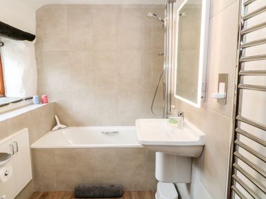 A bathroom with a bathtub sink mirror and heated towel rail at Meadow Lea in Pensilva near Liskeard