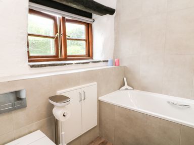 A bathroom with a bathtub a window and a toilet paper holder at Meadow Lea Pensilva near Liskeard