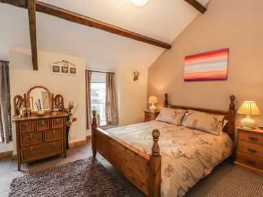 A bedroom with a wooden bed and matching bedside tables with lamps at 60 Hyfrydle Road Talysarn near Caernarfon