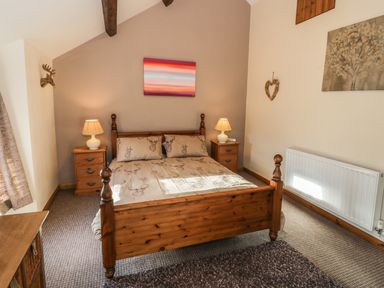 A bedroom with a wooden bed and matching bedside tables with lamps at 60 Hyfrydle Road Talysarn near Caernarfon