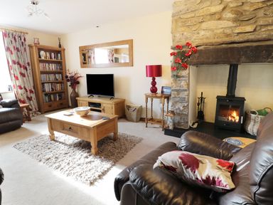 A living room with a stone fireplace a wood stove and a wooden coffee table at 60 Hyfrydle Road in Talysarn near Caernarfon