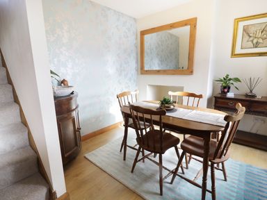 A dining room with wooden table and chairs a large mirror on the wall and a staircase at 60 Hyfrydle Road Talysarn near Caernarfon