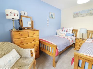 A bedroom with two wooden single beds a wooden chest of drawers a wooden bedside table and a wicker chair at 60 Hyfrydle Road Talysarn near Caernarfon