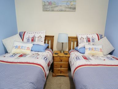 A bedroom with two single beds with wooden headboards and a wooden bedside table with a lamp at 60 Hyfrydle Road Talysarn near Caernarfon