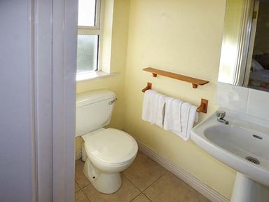A bathroom with a toilet sink and towel rack with towels at Number 12 in Mulranny County Mayo