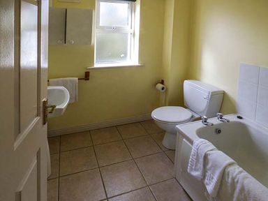 A bathroom with a bathtub a toilet and a sink with a towel at Number 12 in Mulranny County Mayo
