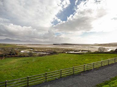 A fenced green field with water channels and hills in the background at Number 12 Mulranny County Mayo