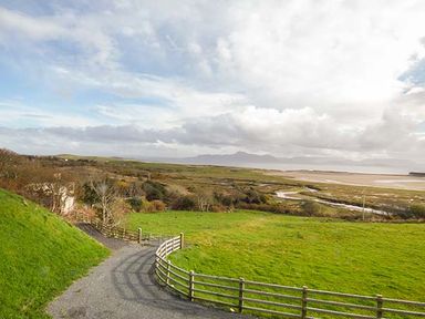 A rural landscape with a gravel road and wooden fence overlooking fields and distant hills at Number 12 in Mulranny County Mayo