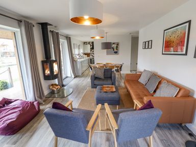 A living room with chairs sofa a bean bag and a wood burning stove at Lily-pad Lodge in Thorpe-on-the-Hill