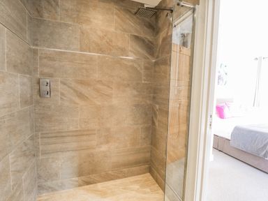 A bathroom with a tiled walk-in shower beside a door leading to a bedroom at Lily-pad Lodge in Thorpe-on-the-Hill