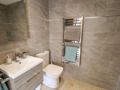 A bathroom with a sink cabinet toilet and towel rail with towels at Lily-pad Lodge in Thorpe-on-the-Hill
